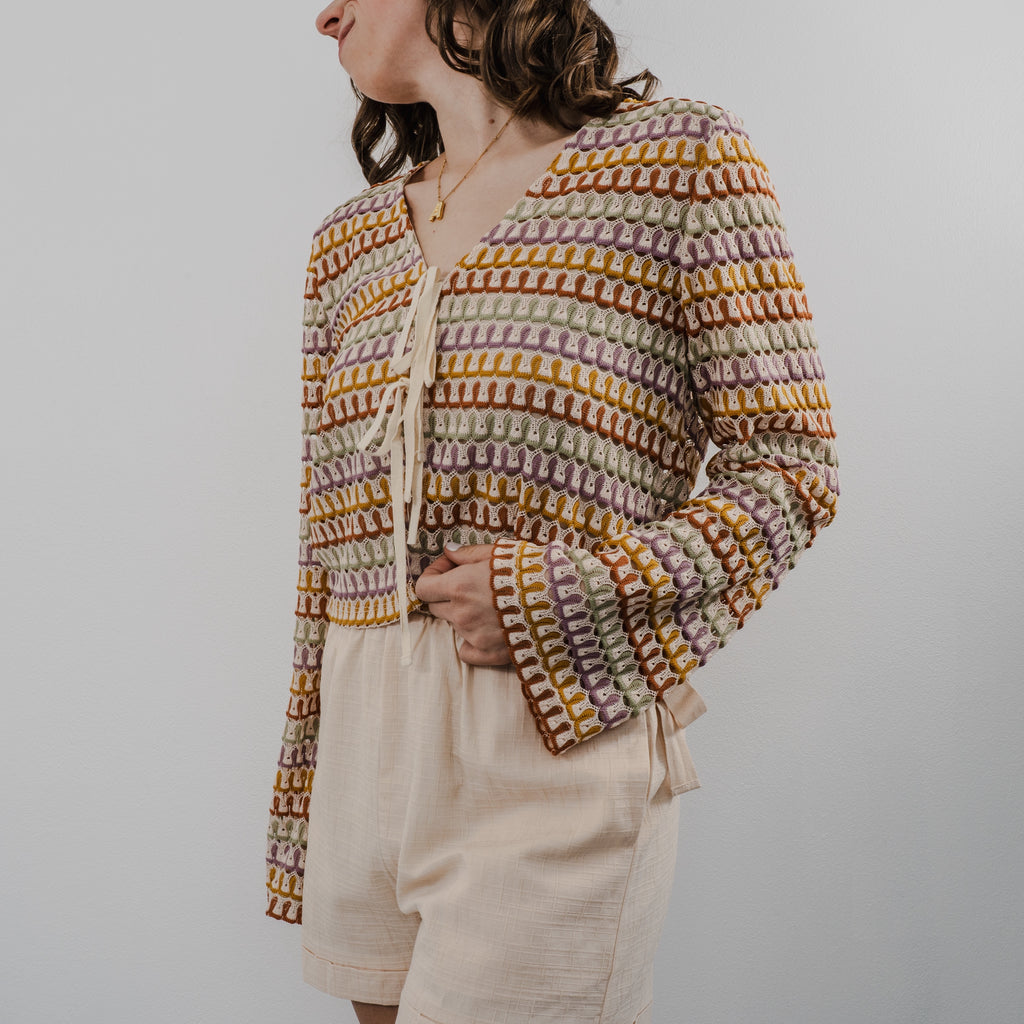 Side view of the textured crochet pattern and closures are string tied as bows on The Heirloom Crochet Cardigan.