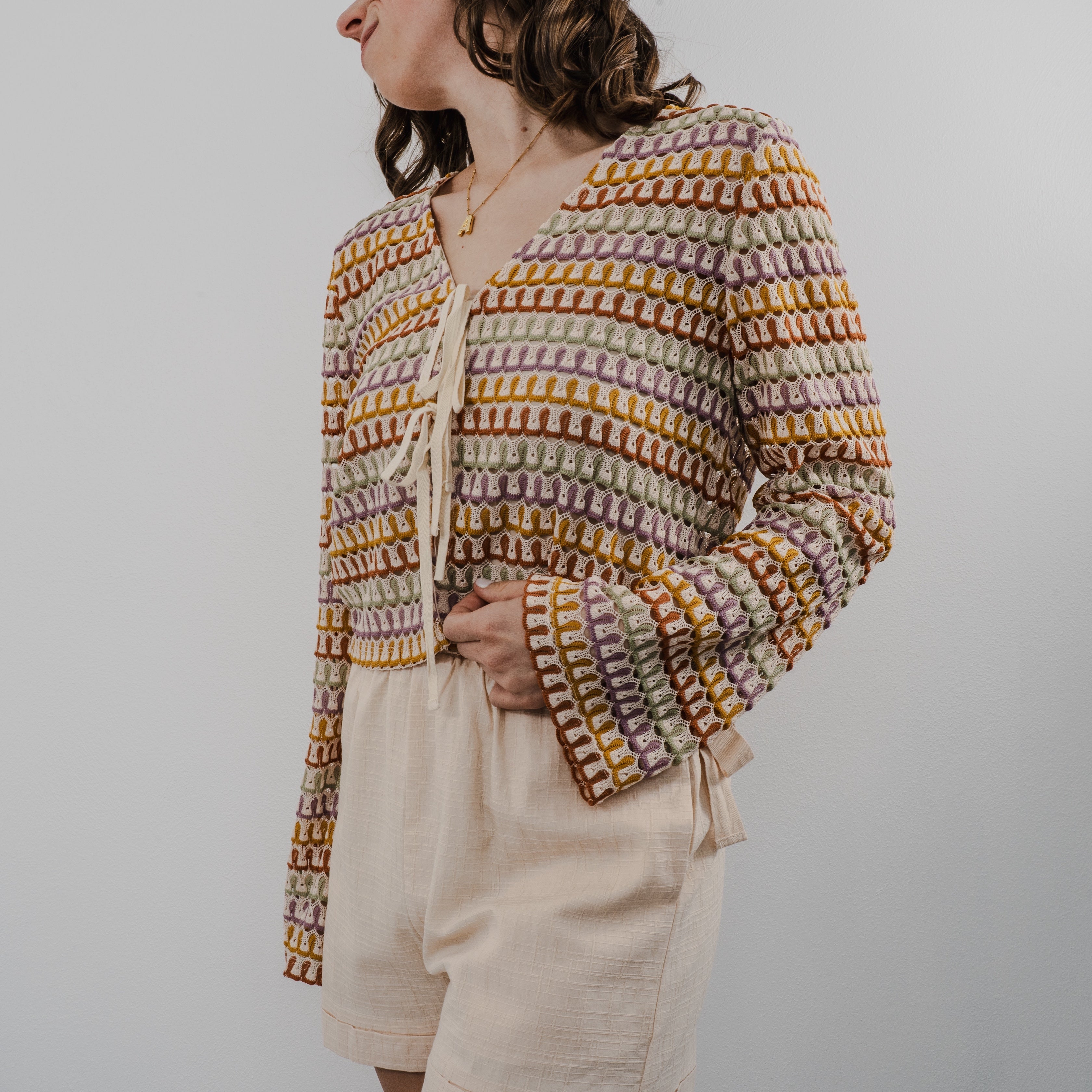 Side view of the textured crochet pattern and closures are string tied as bows on The Heirloom Crochet Cardigan.