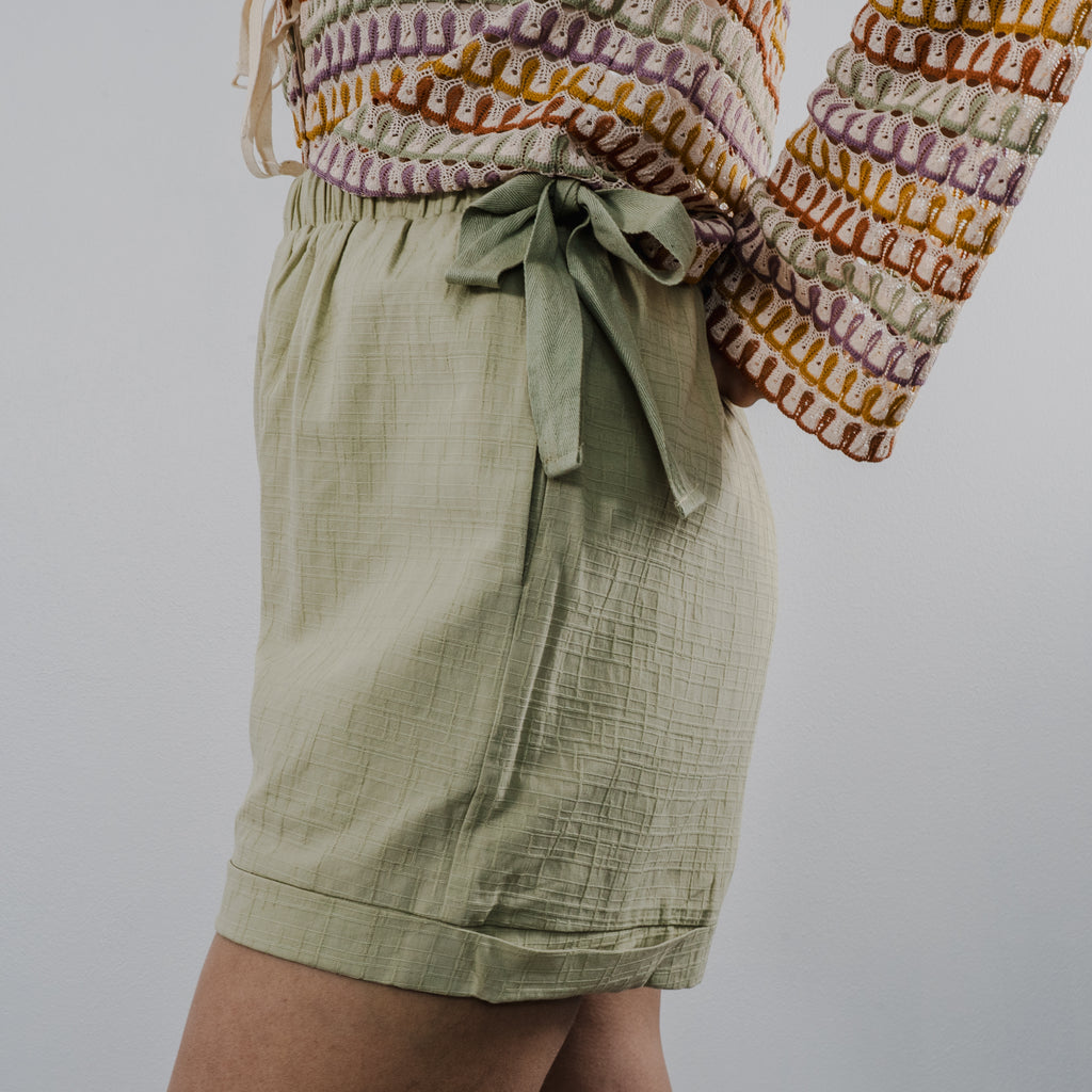 Side view of the heirloom crochet tie shorts showing the textured knit pattern and comfortable fit. Bows on the side.