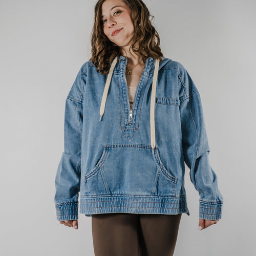 Model wearing a medium-wash denim-style hoodie with a relaxed oversized fit and adjustable hood strings.