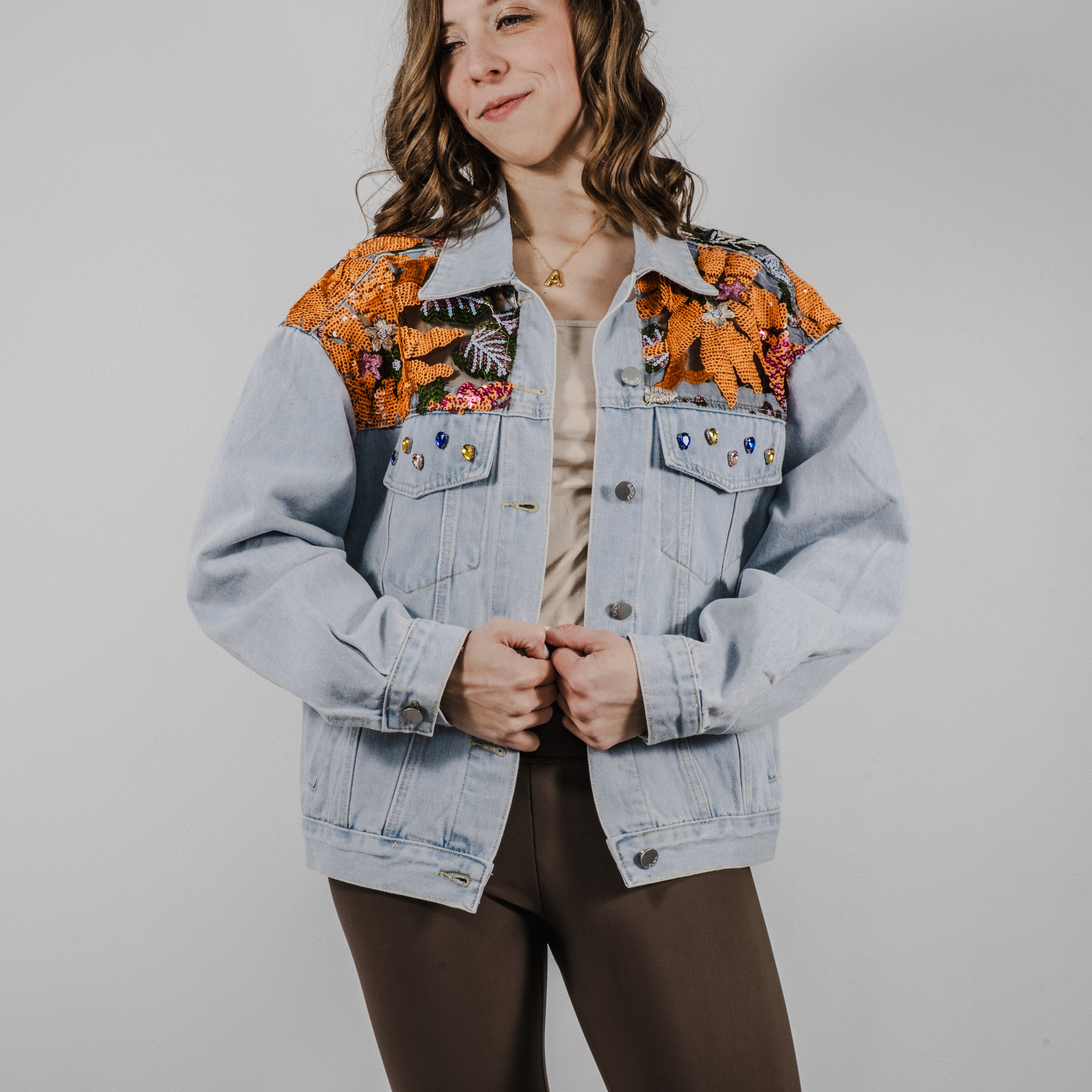 A light-wash denim jacket with an oversized fit, featuring intricate sequined patterns that catch the light.