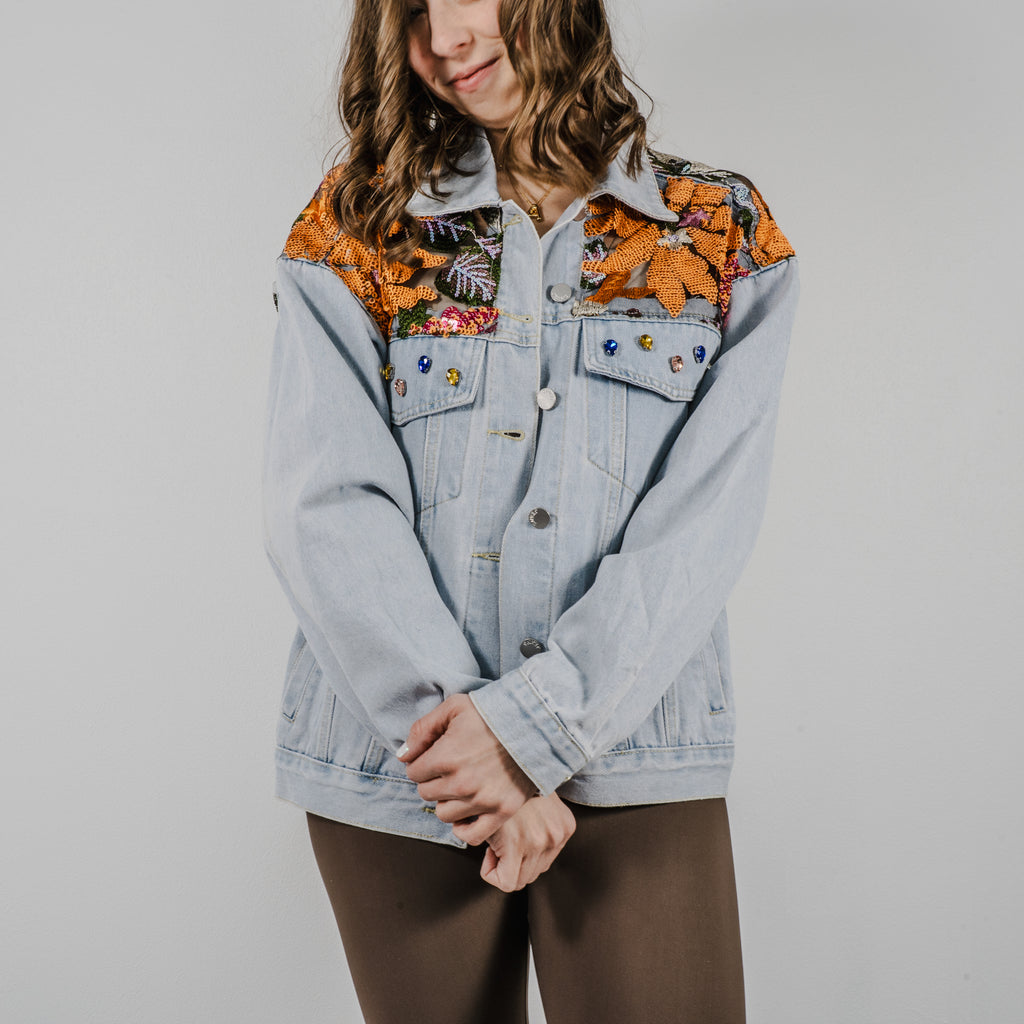 A light-wash denim jacket with an oversized fit, featuring intricate sequined patterns that catch the light.