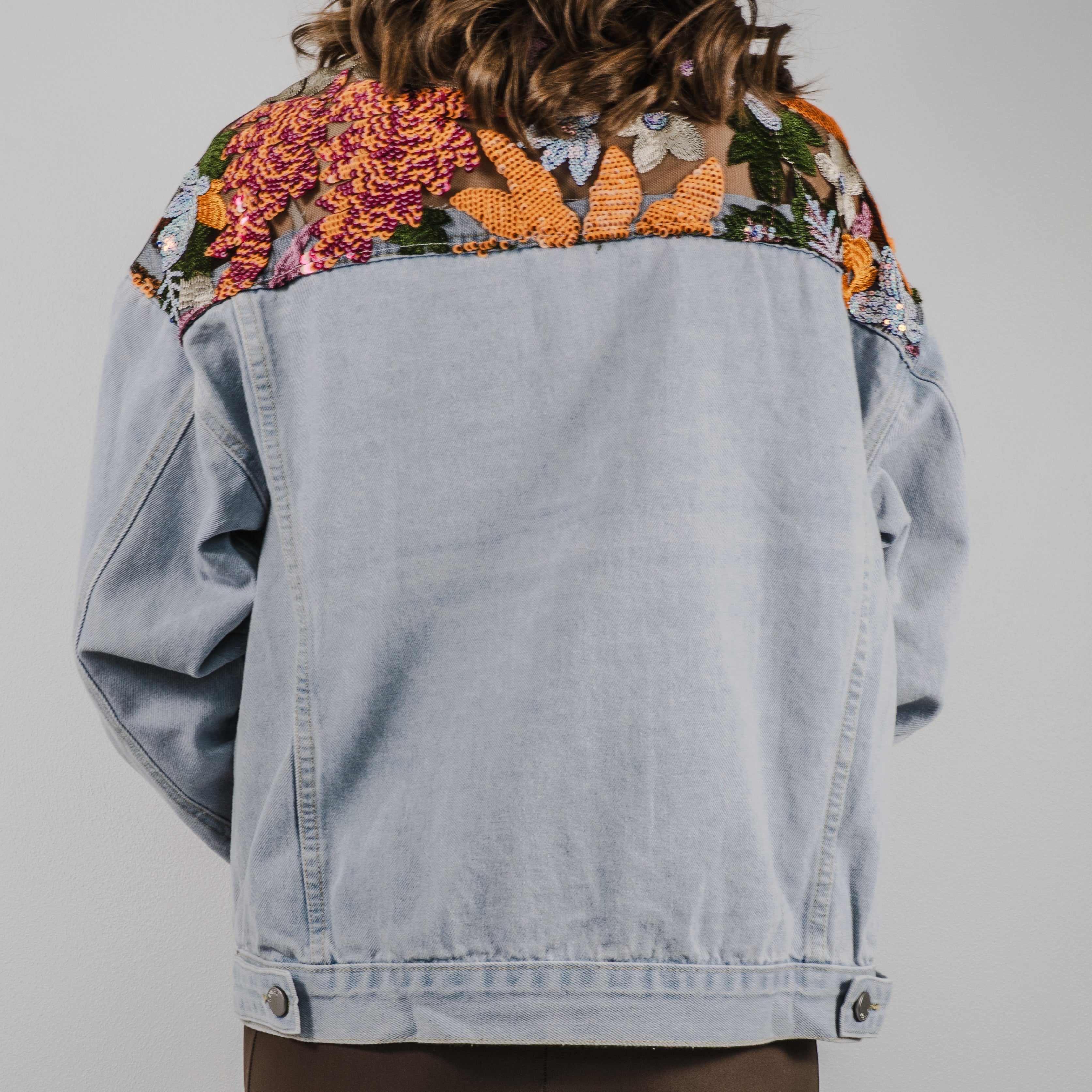 A close up of the back of the Set Free denim jacket showing a large, detailed sequin design across the shoulders.