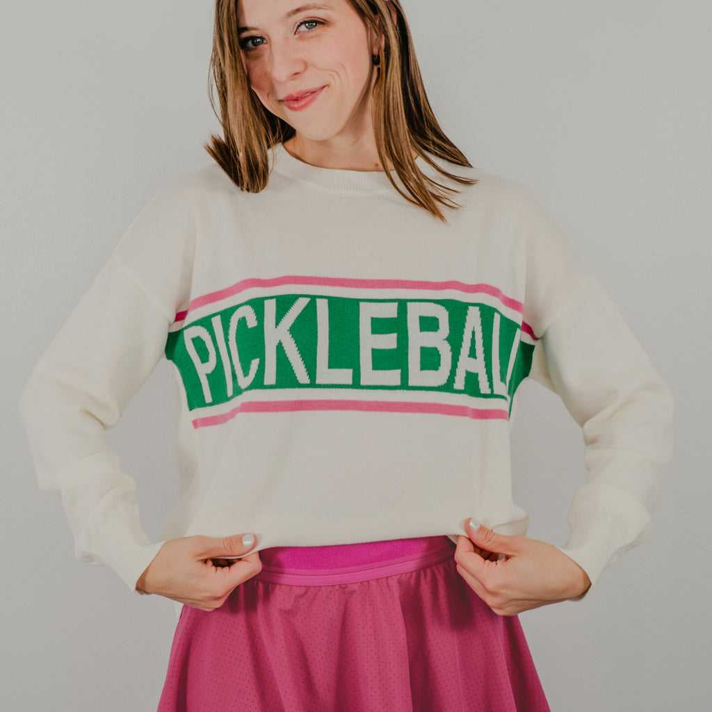 Model pulls sweater to read the full wording "PICKLEBALL" on the vintage design of the Pickleball Club Sweater.