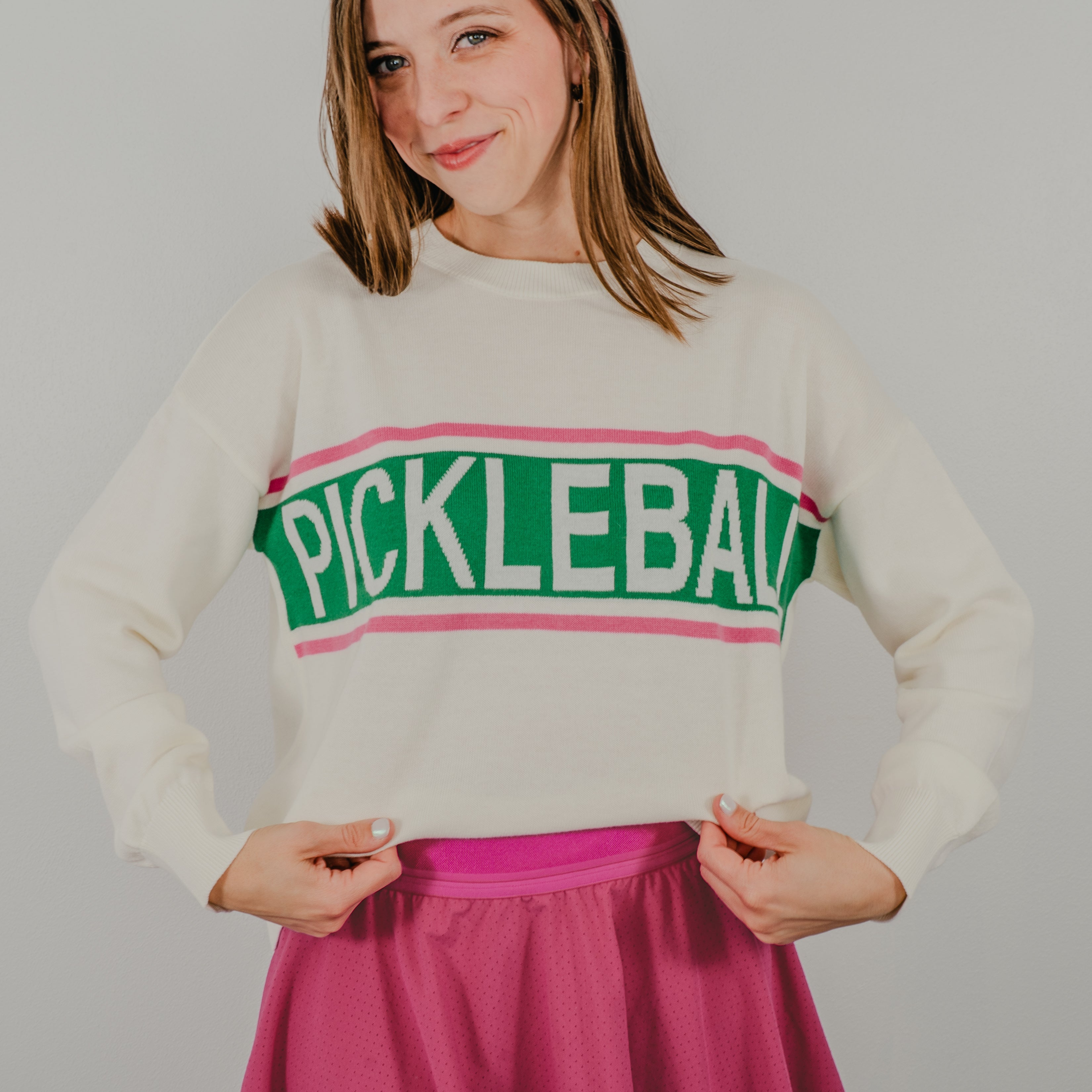 Model pulls sweater to read the full wording "PICKLEBALL" on the vintage design of the Pickleball Club Sweater.