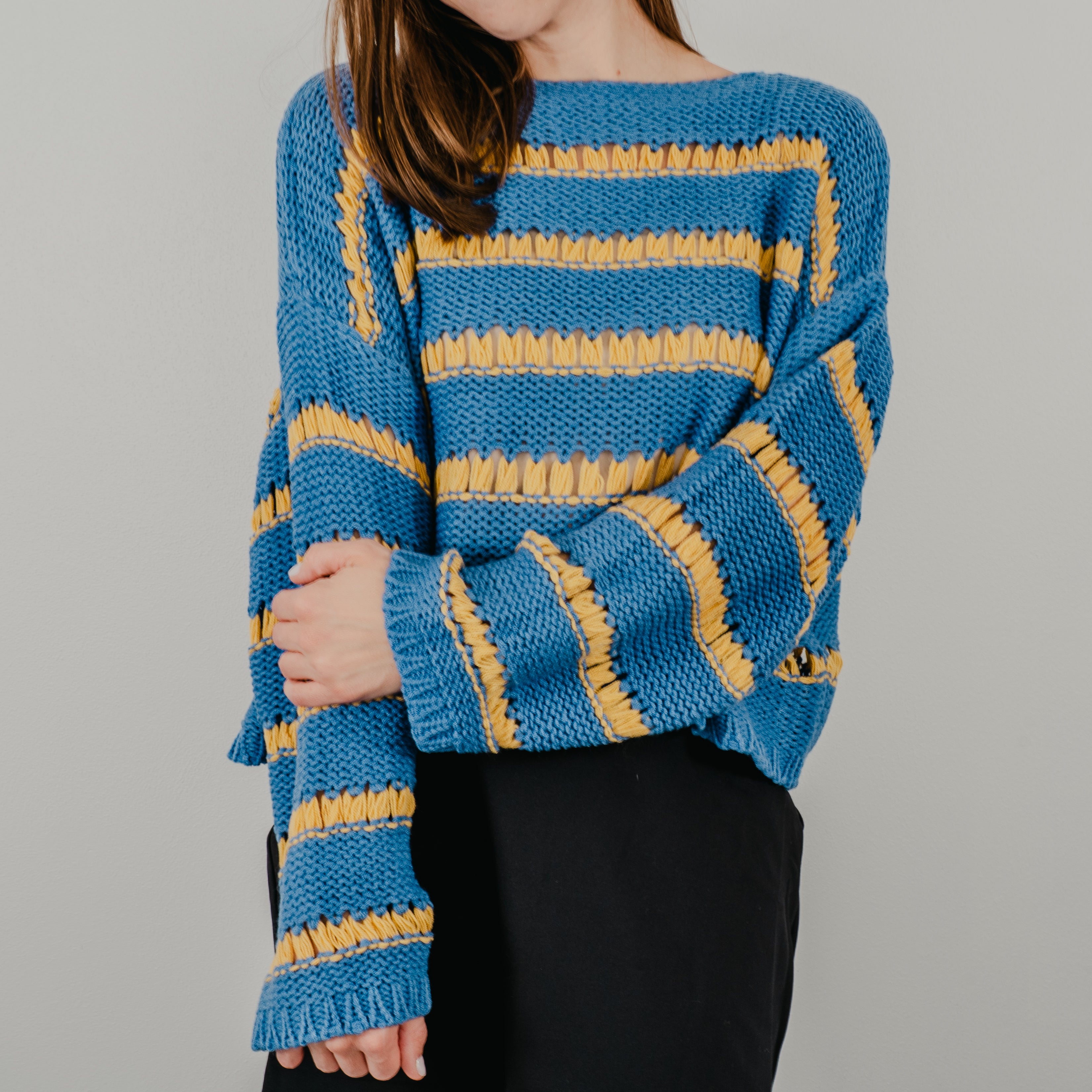 Up close shot of the knit detailing of the Ode to Gloria Knit Sweater, showing blue and yellow stripes.