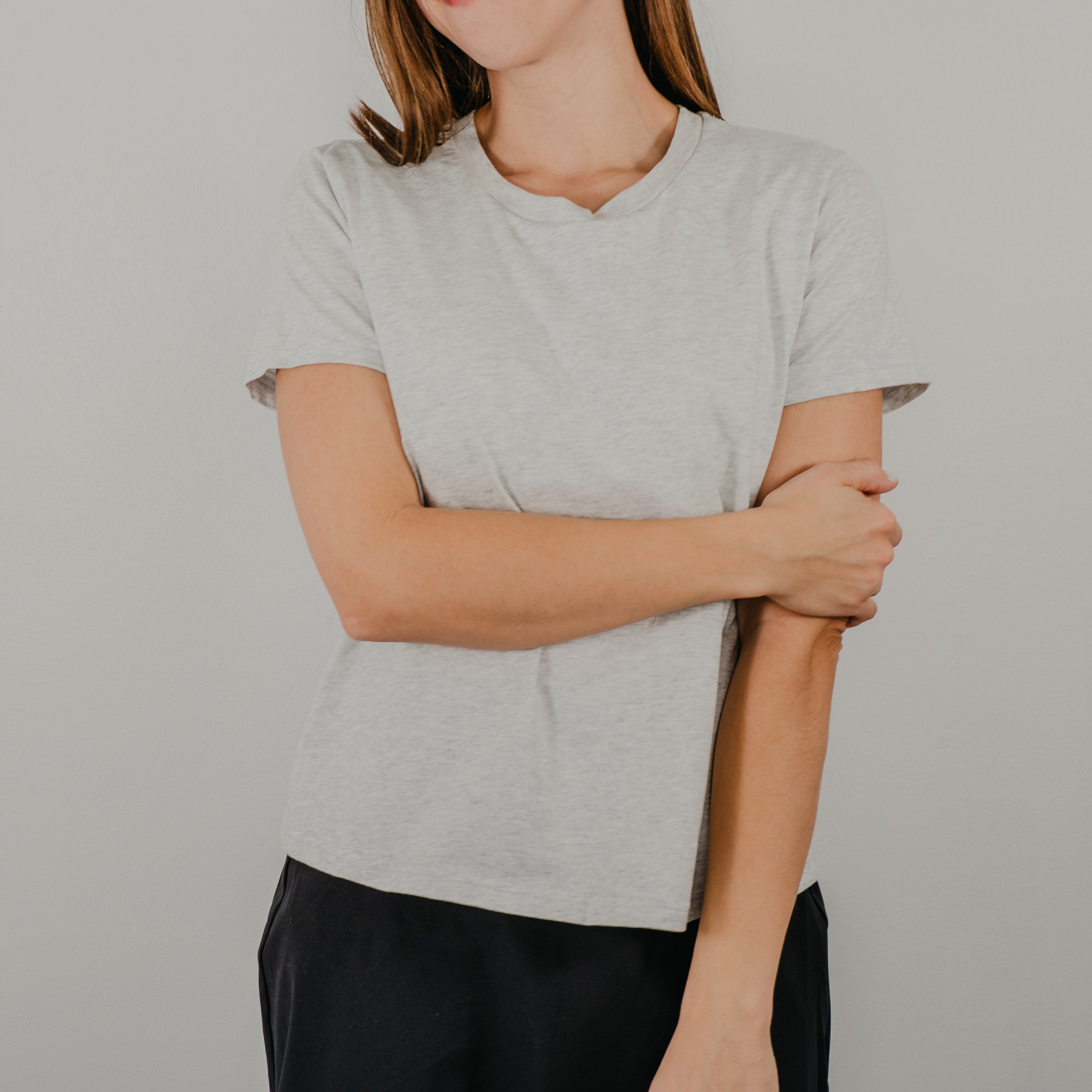 Model wearing the light heathered grey Basic Bra Tee styled over an athletic skirt for a classic, effortless look.