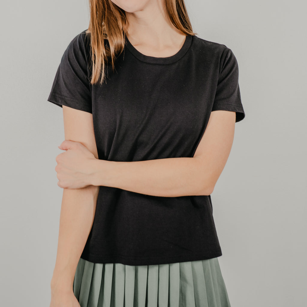 Model wearing the black Basic Bra Tee styled over an athletic skirt for a classic, effortless look.