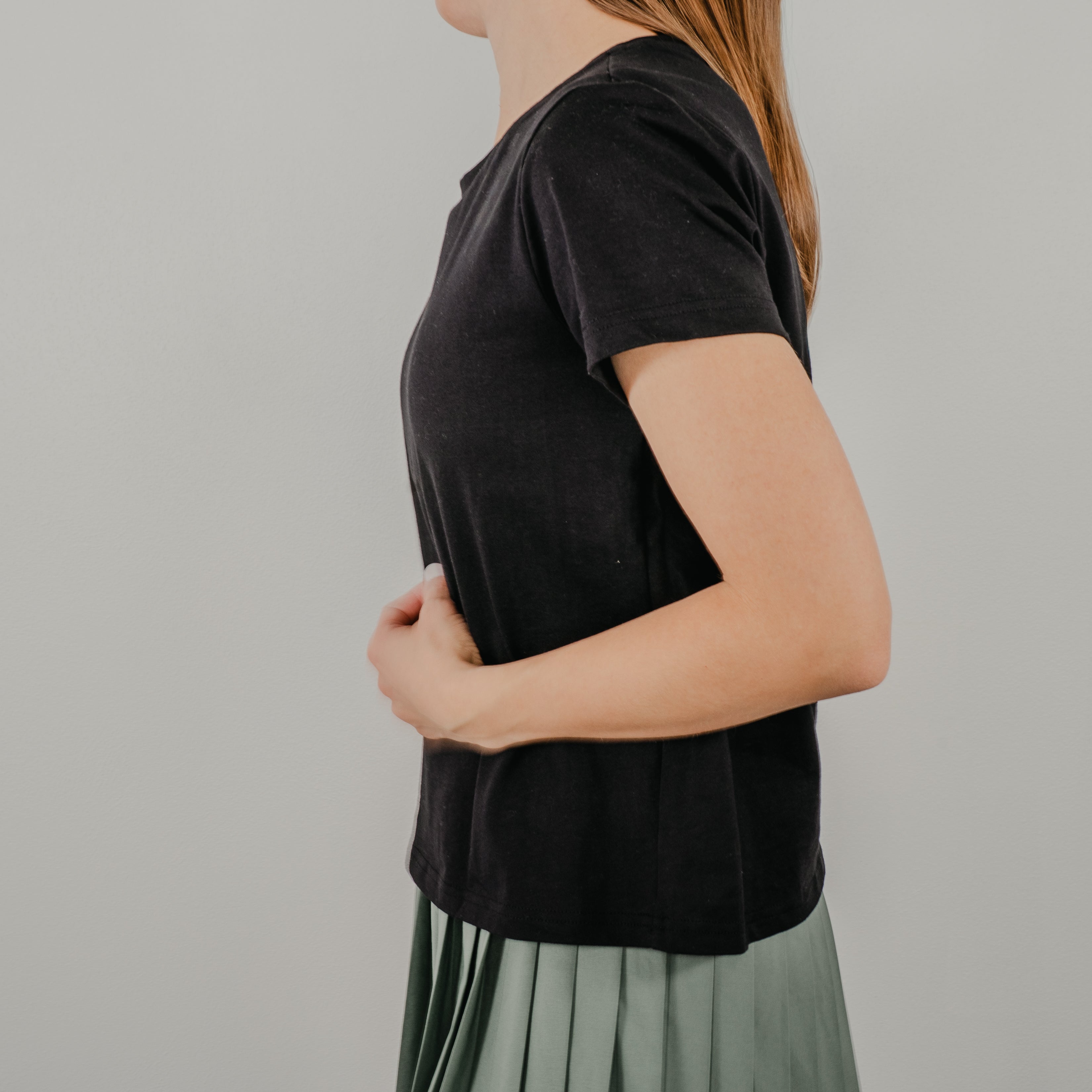 Side view of the black Basic Bra Tee showing the clean, seamless design and where the shirt comes down to the waist in length.