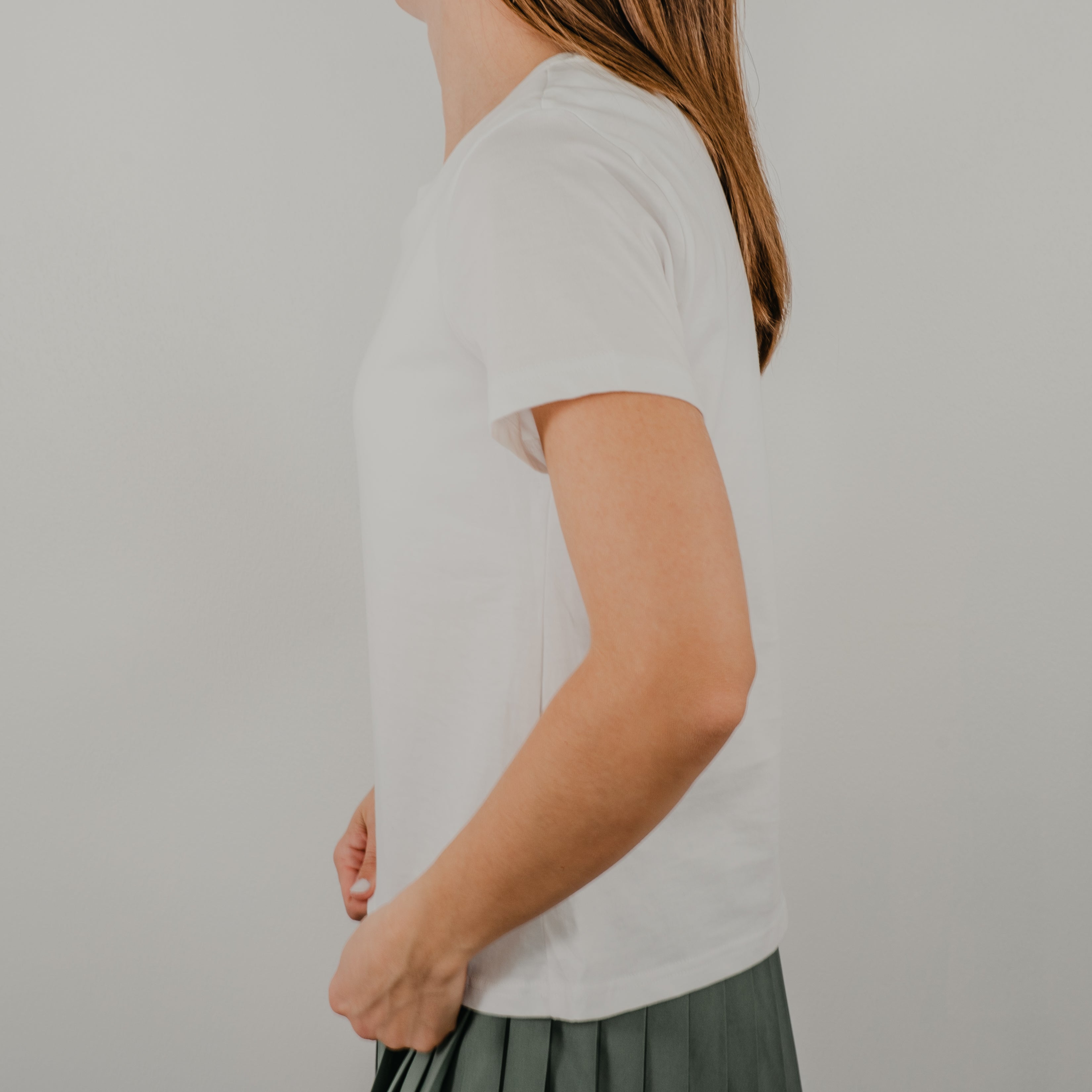 Side view of the white Basic Bra Tee showing the clean, seamless design and length of the top that hits at the waist.