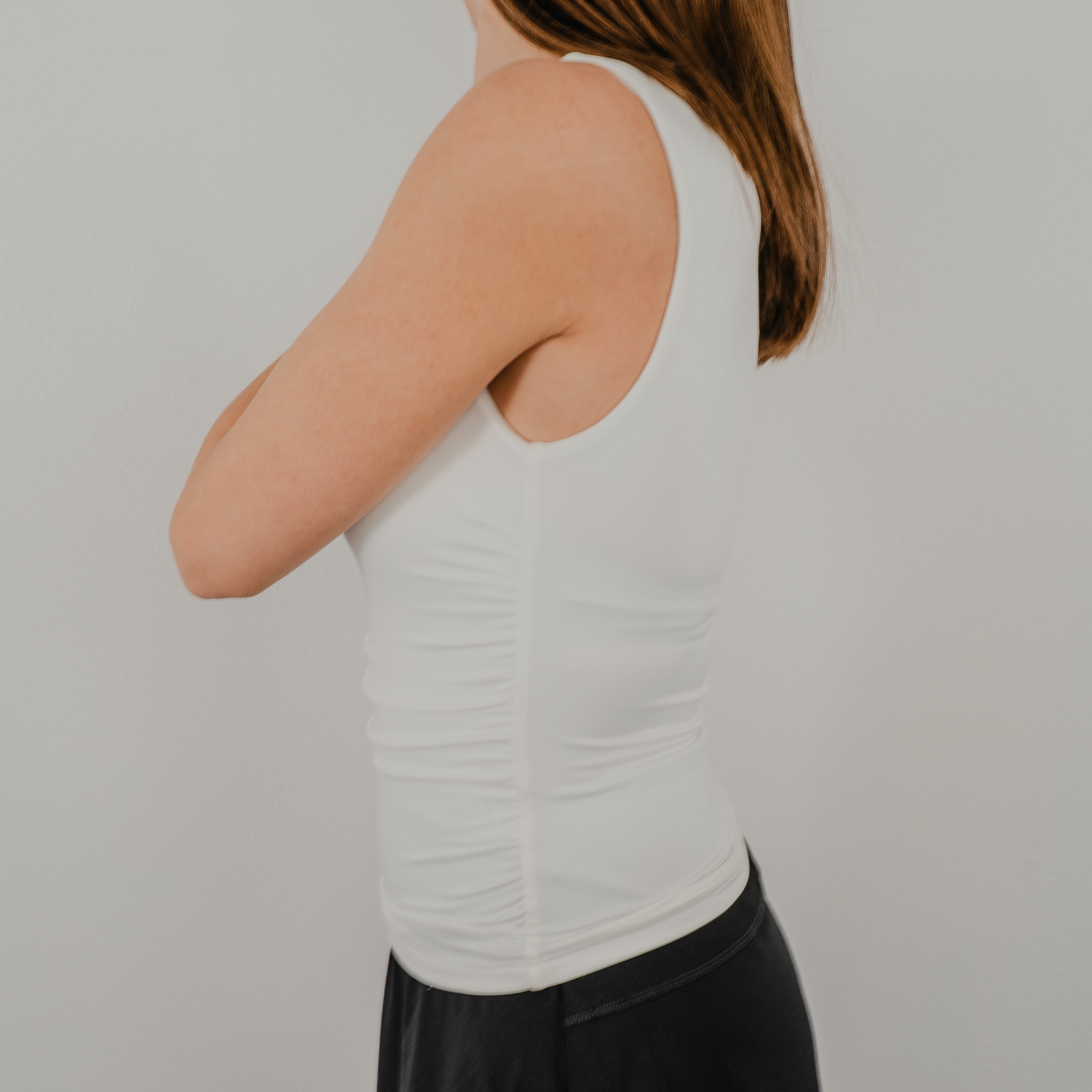Side view of the Second Skin Tank showcasing the flattering stretch fit and waist-length hem. Ruched design on the side.