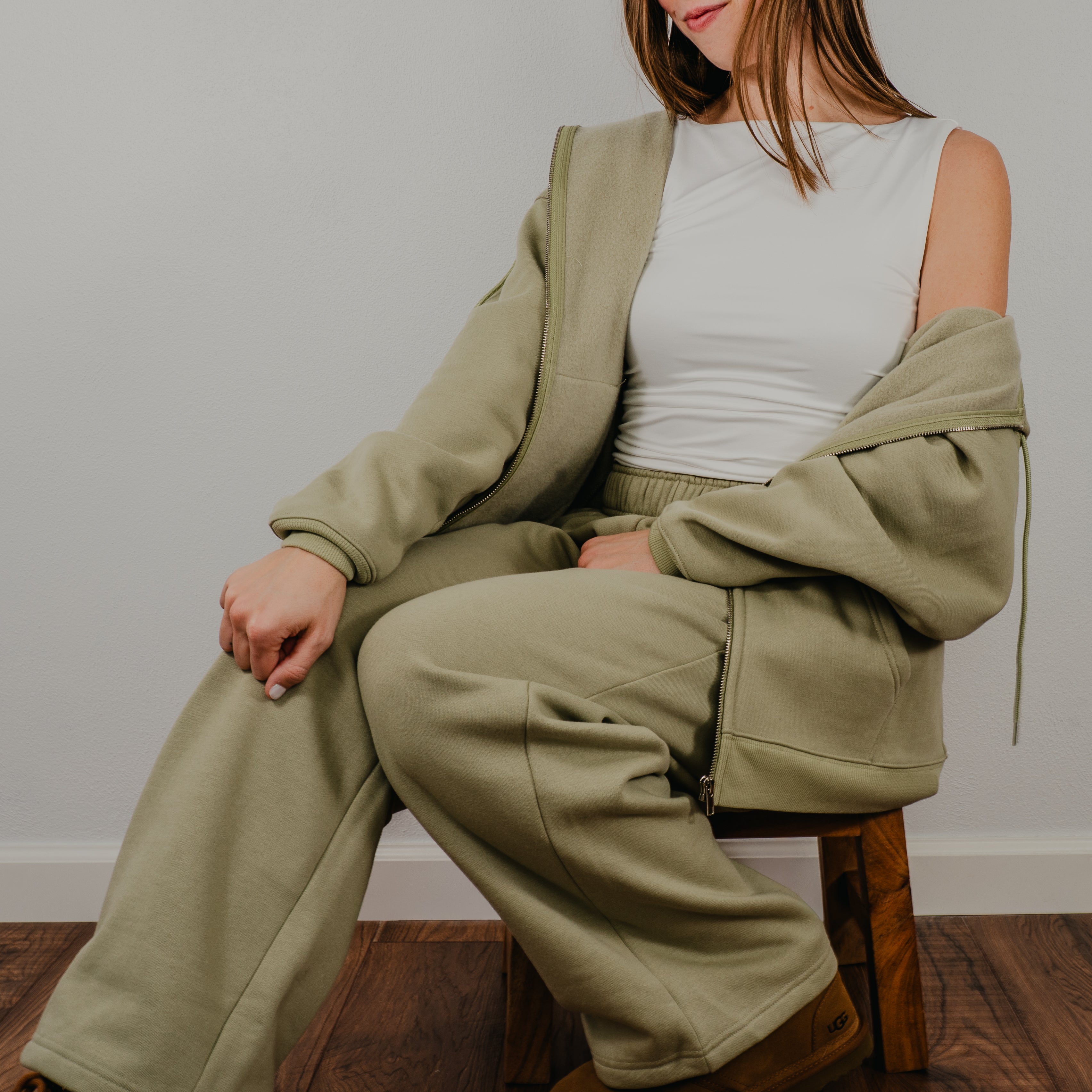 Shows model wearing a two-piece lounge set in a deep fern green, featuring a matching oversized full zip sweatshirt and relaxed-fit joggers.