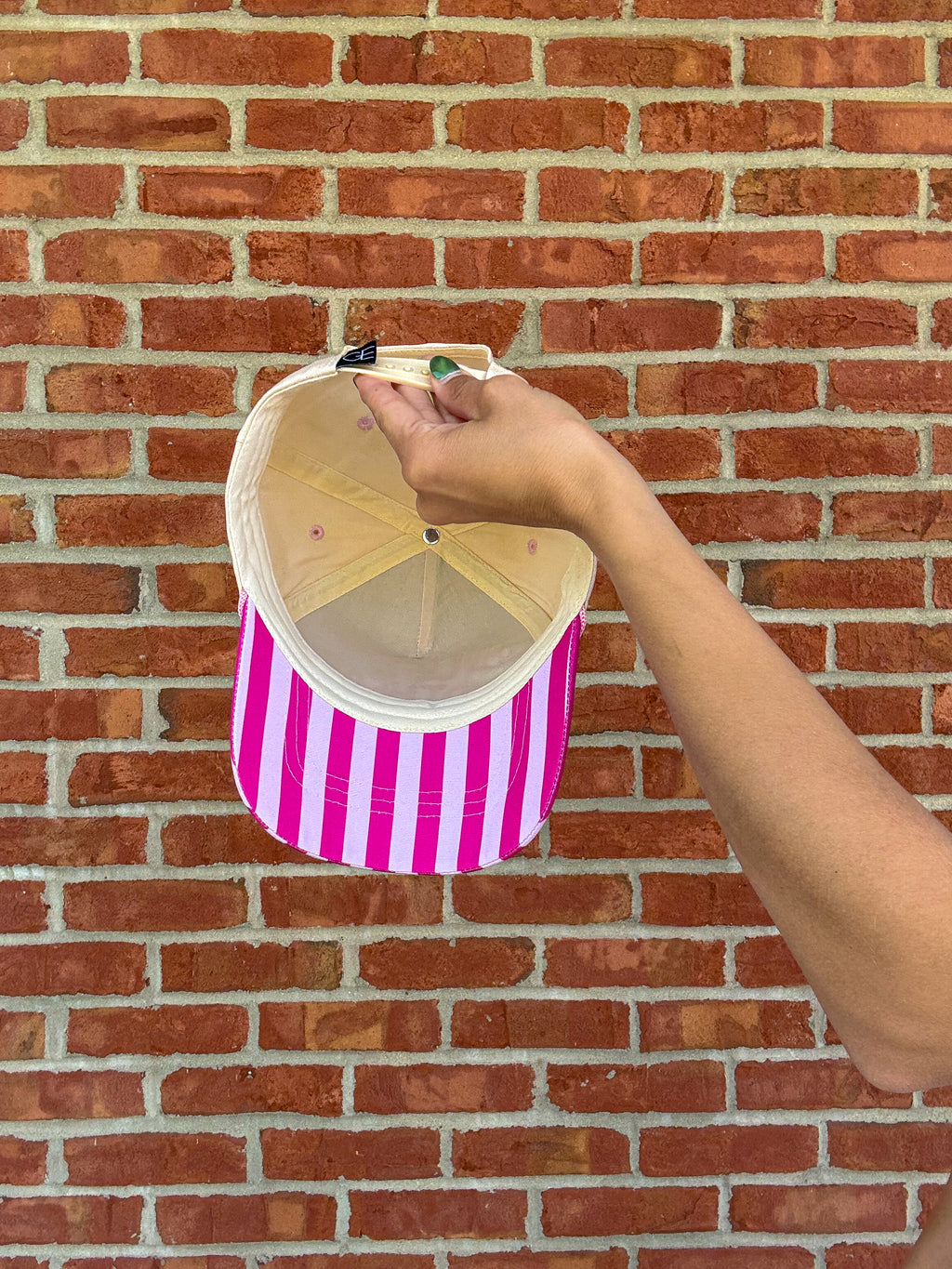 ballcap with striped against a brick wall