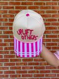 Cap with 'Uplift Others' text against a brick wall