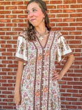 Woman wearing a floral dress standing against a brick wall